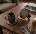 Ceramic mug on a coaster with a decorative coaster holder on a wooden table.