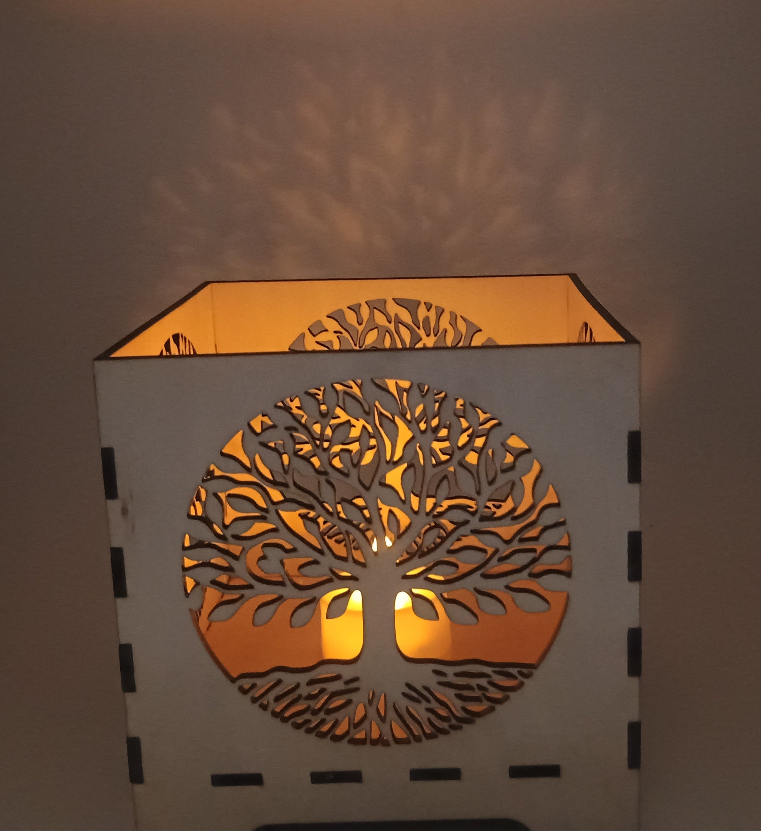 Decorative lamp with tree-of-life design on a plain background