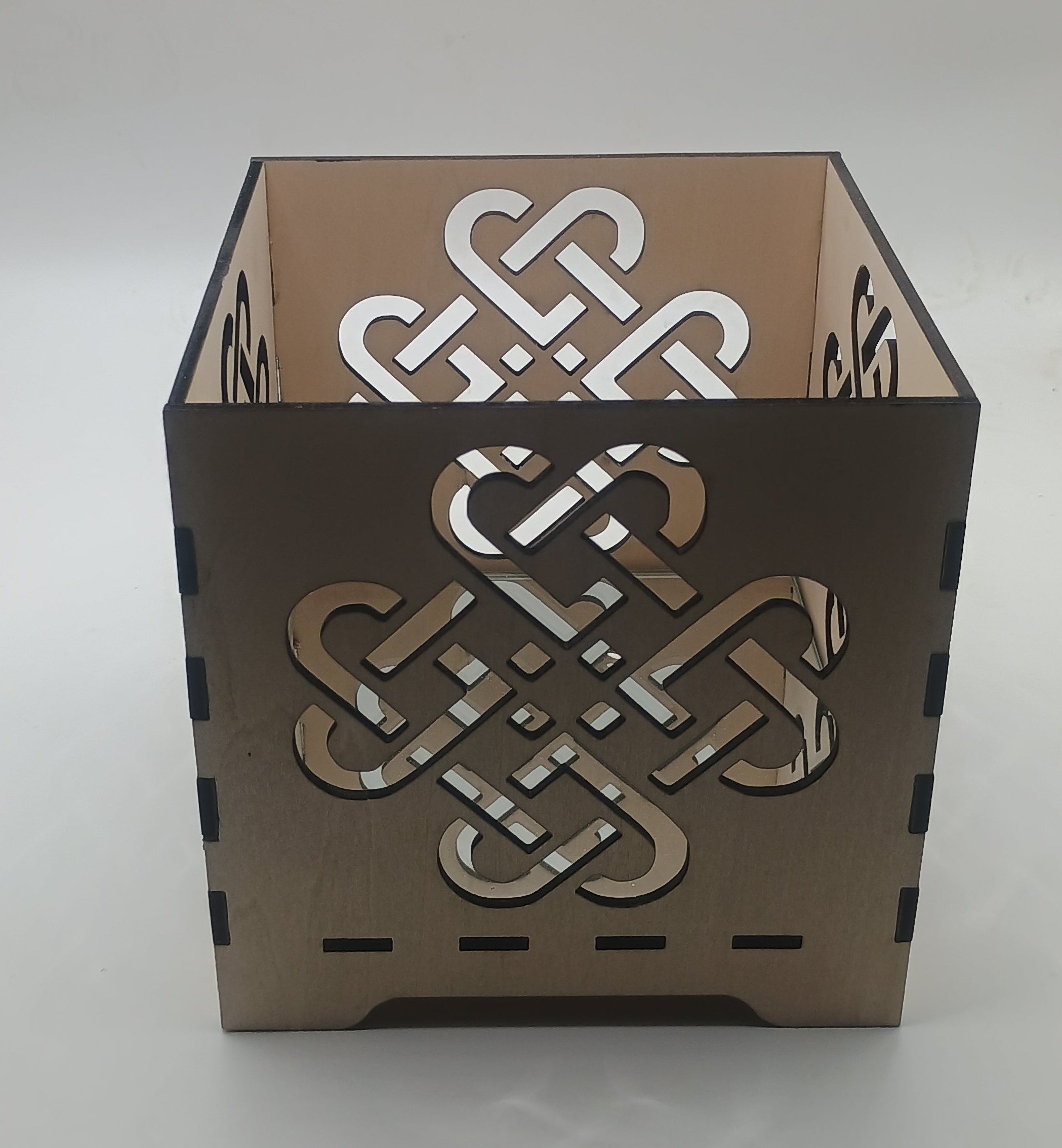 Decorative candle holder with Celtic knot design on a neutral background