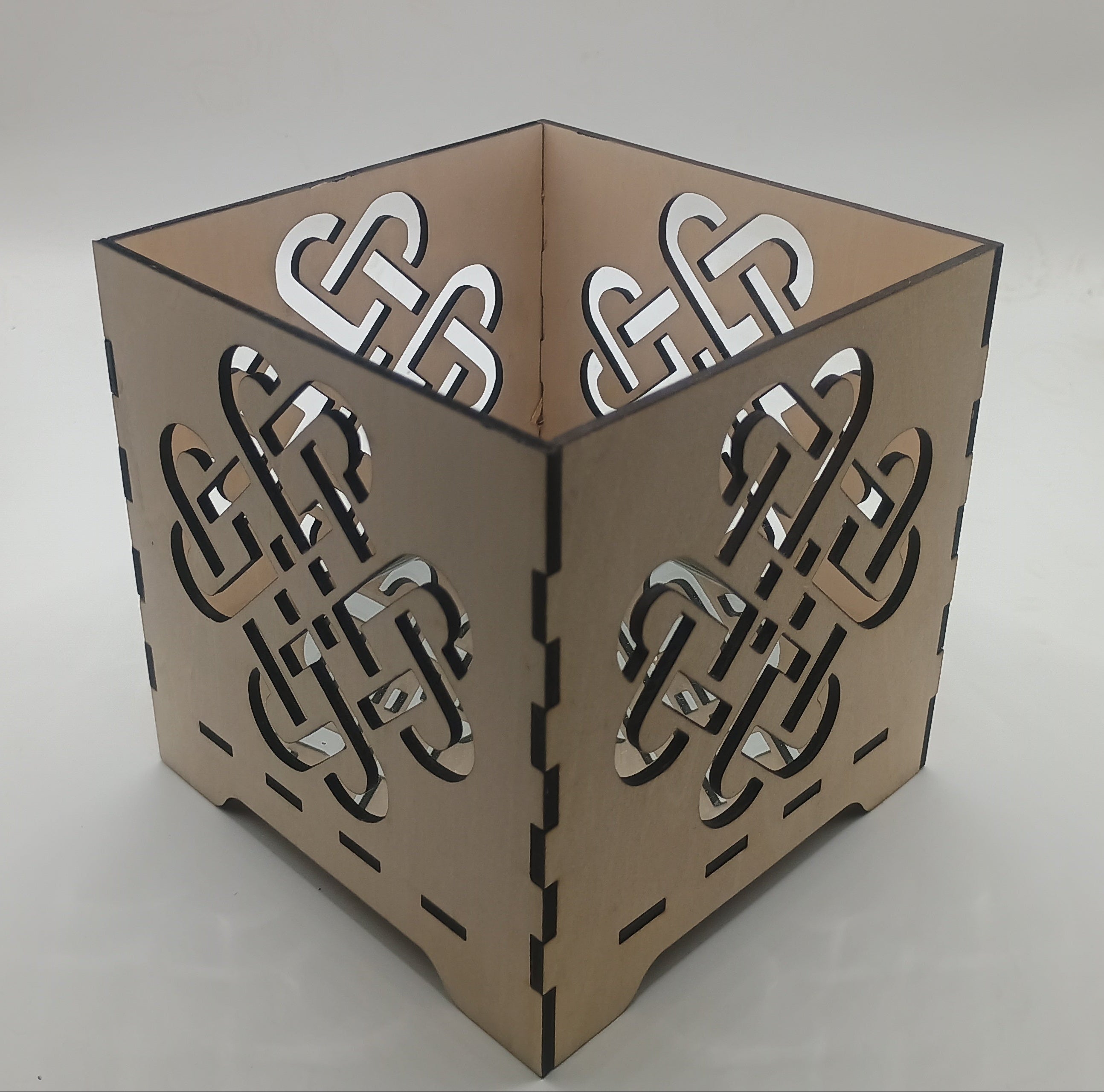 Decorative candle holder with Celtic knot design on a neutral background