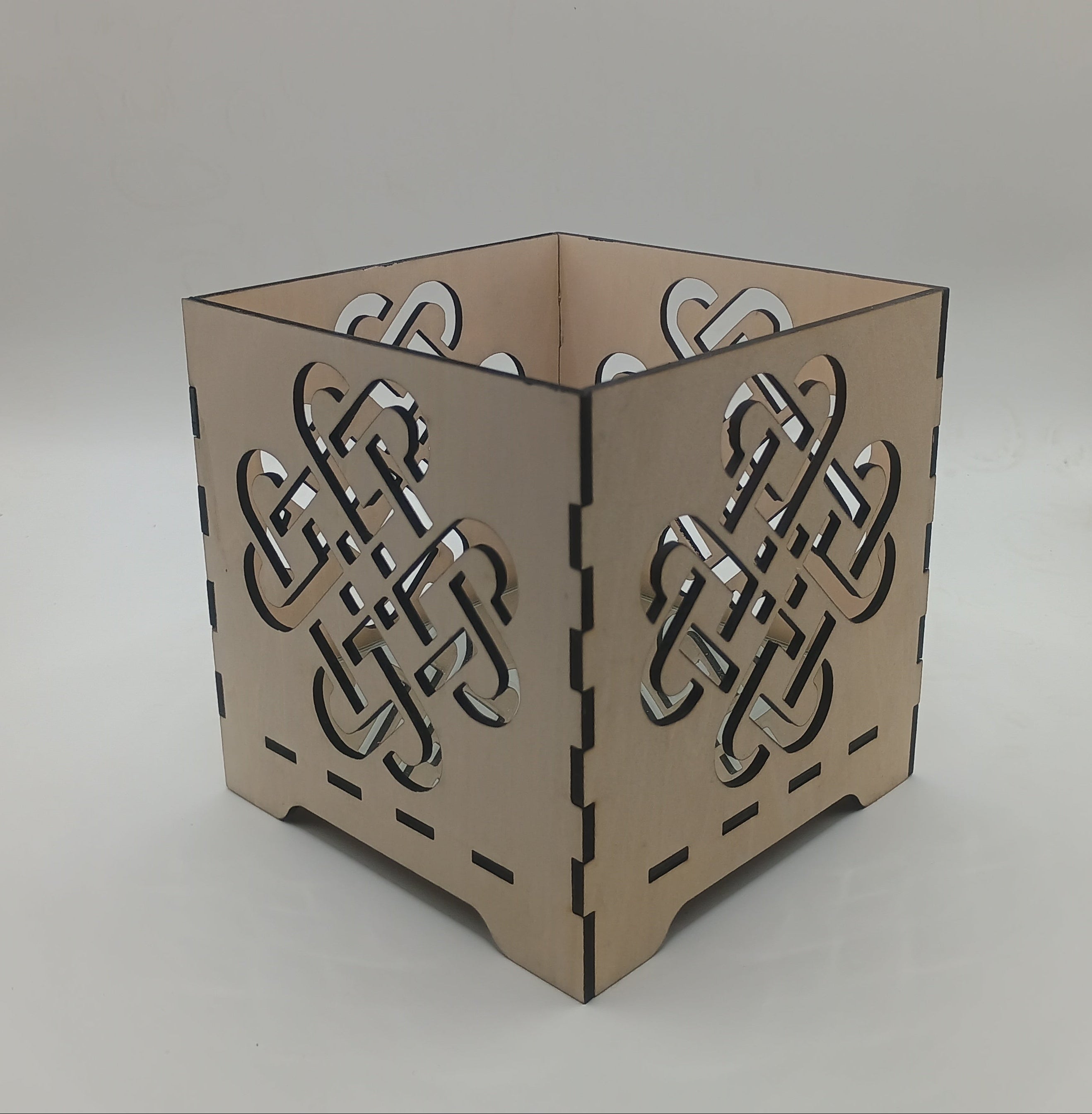 Decorative candle holder with Celtic knot design on a neutral background