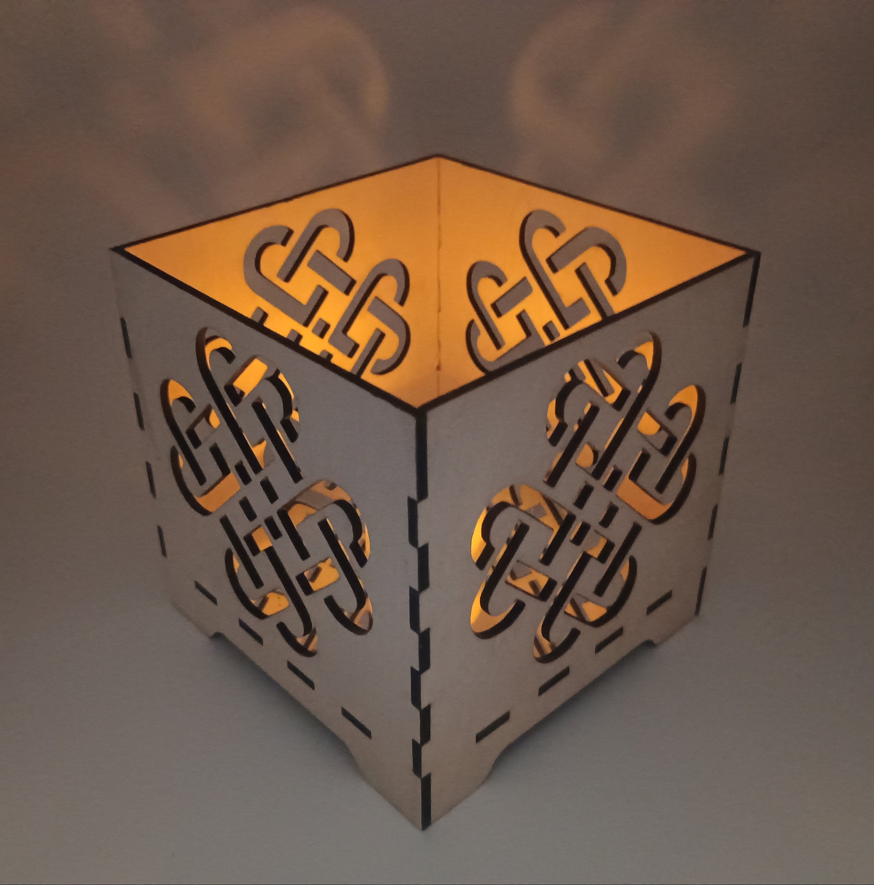 Decorative candle holder with intricate cut-out patterns on a neutral background