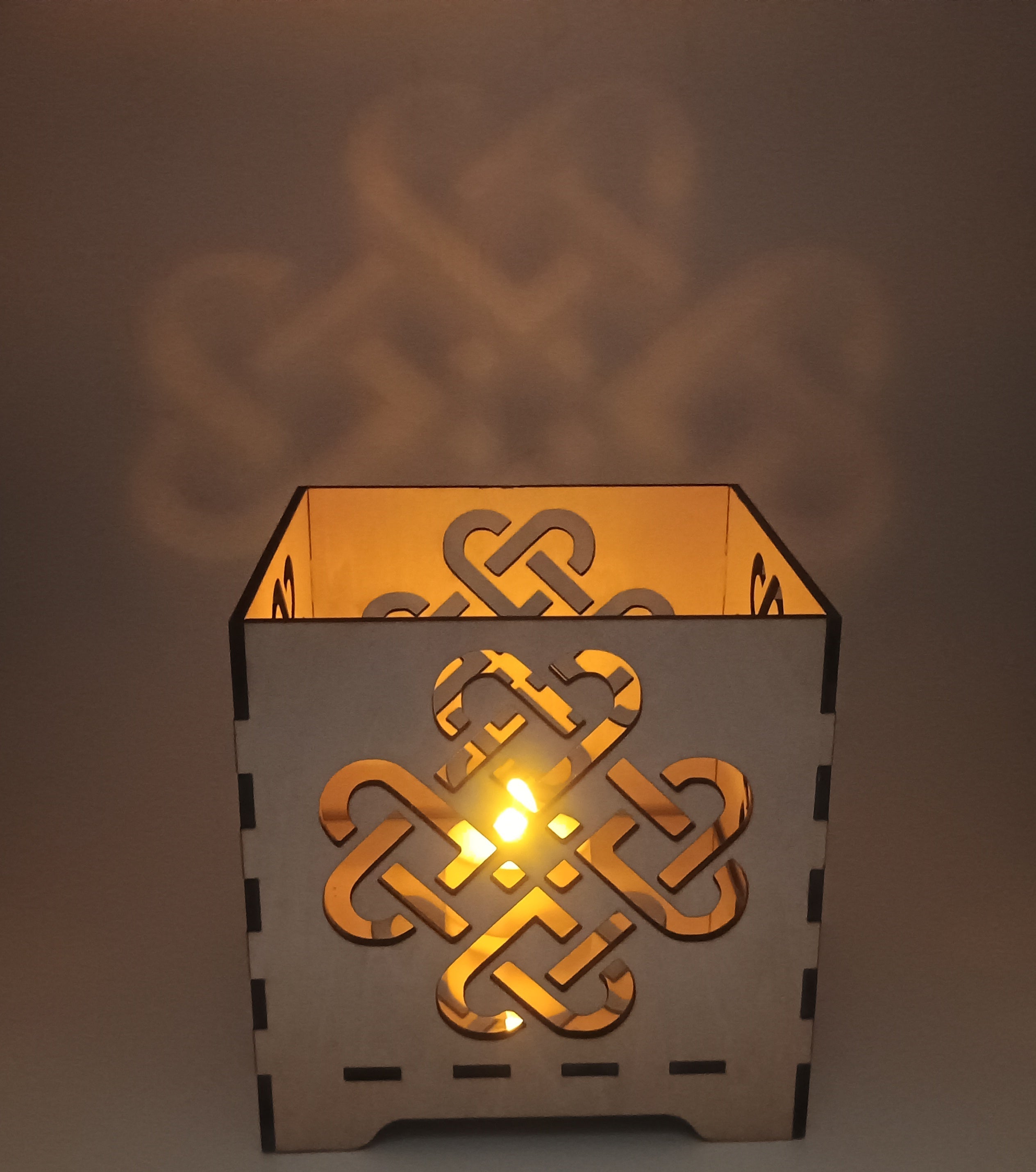 Decorative candle holder with Celtic knot design on a neutral background