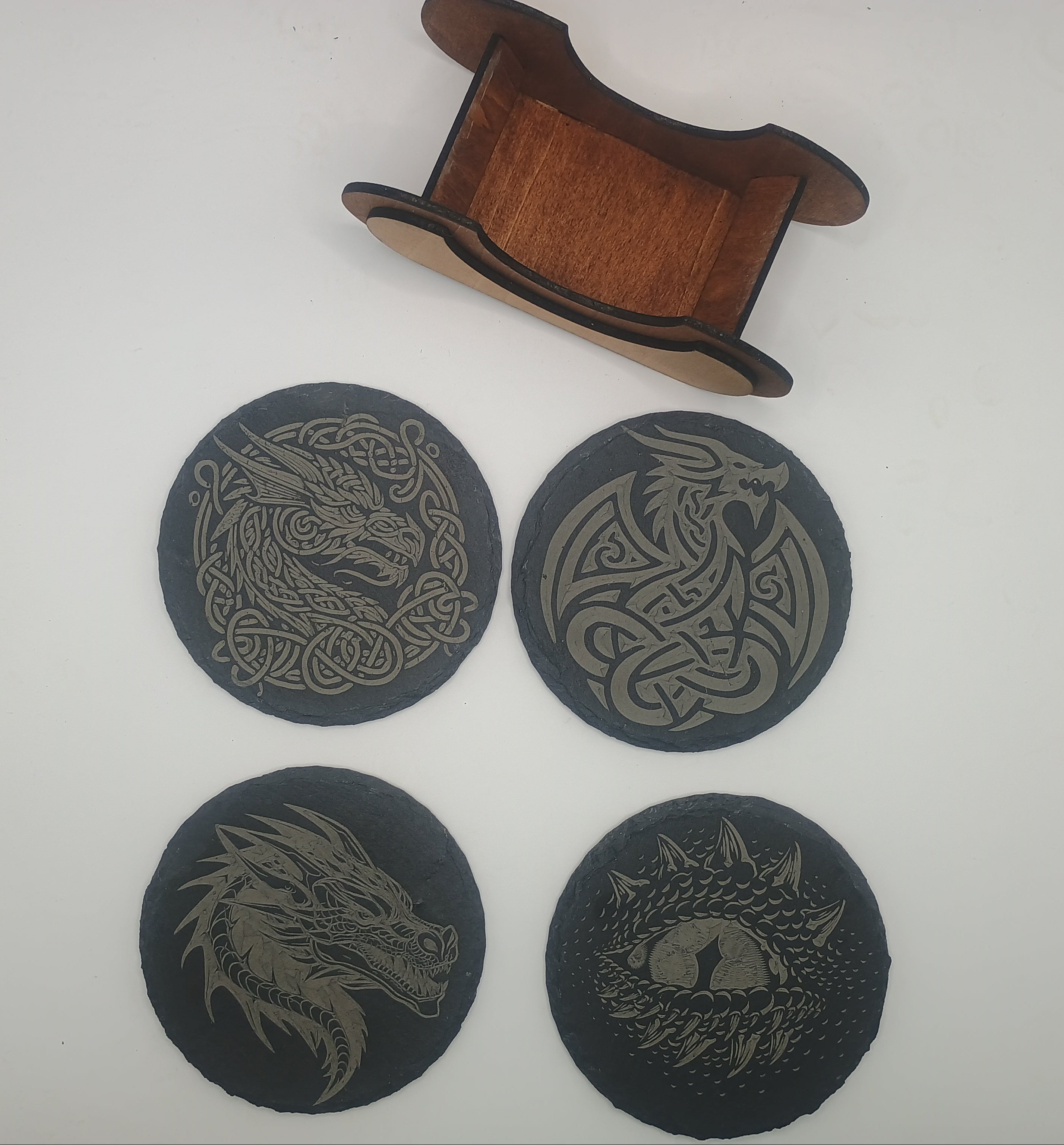 Four dragon-themed coasters with a wooden coaster holder.