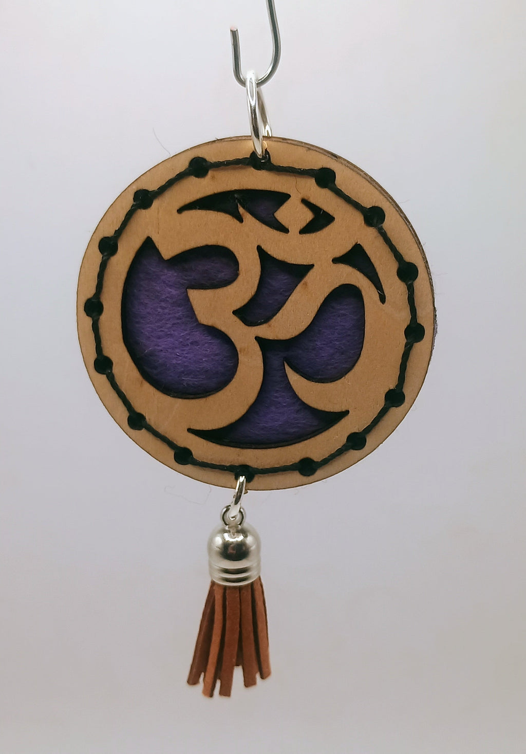 Decorative hanging ornament with Om symbol and tassel on a white background