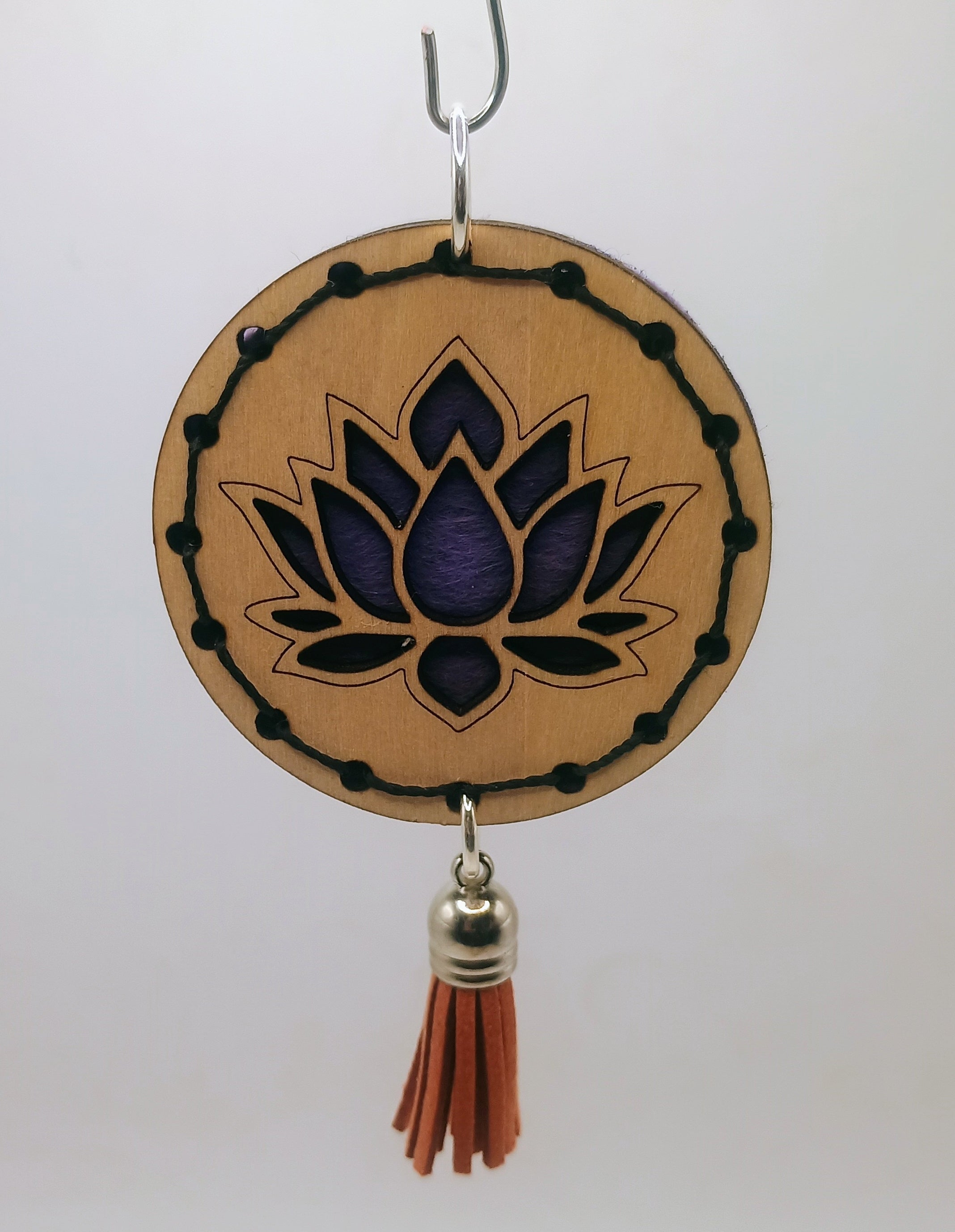 Decorative hanging item with purple lotus design and red tassel on a white background