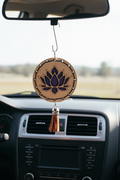 Decorative hanging item with purple lotus design and red tassel hanging off a rearview mirror