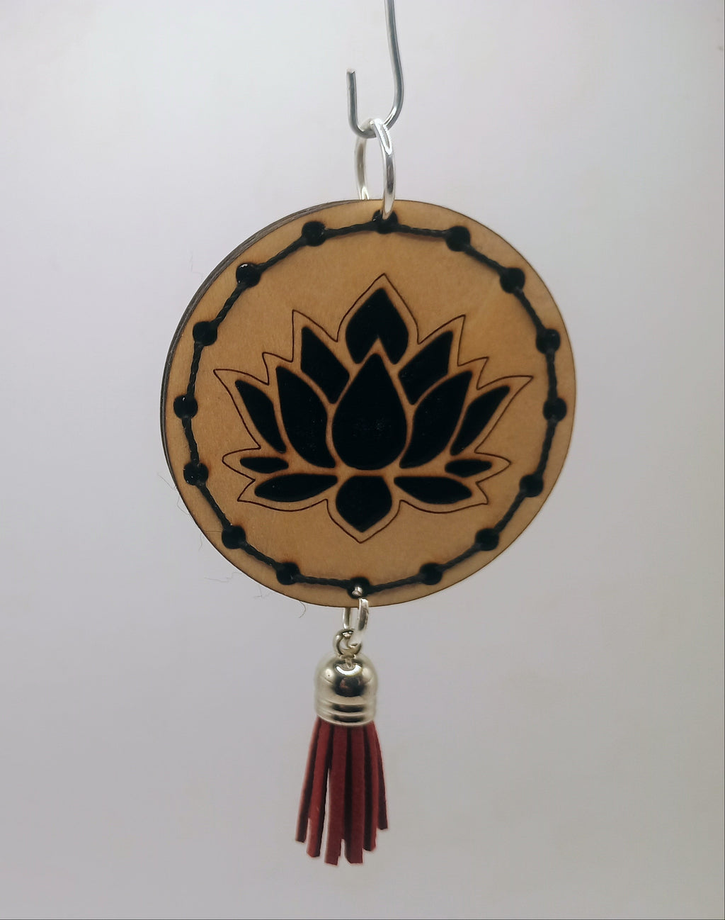 Decorative hanging item with lotus design and tassel on a white background
