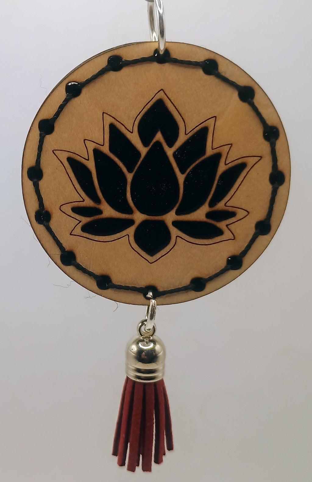Decorative hanging item with lotus design and tassel on a white background