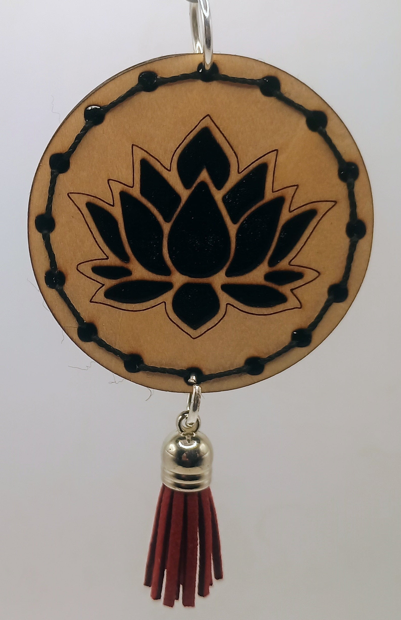 Decorative hanging item with lotus design and tassel on a white background