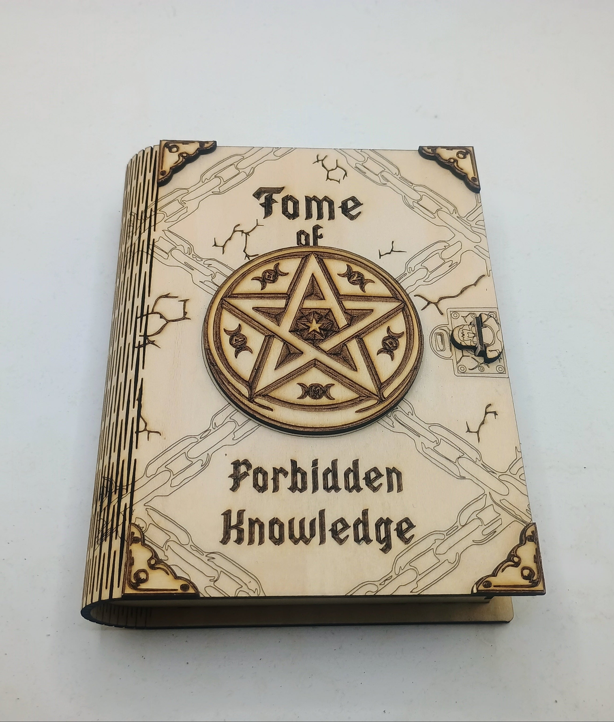 A small decorative book titled 'Fome of Forbidden Knowledge' with a large circular pentagram emblem on the cover, photographed on a plain light background.