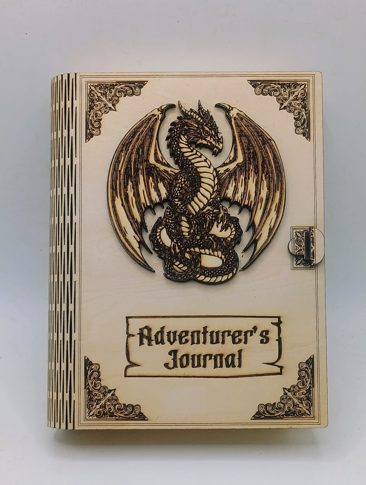 A wooden box titled 'Adventurer's Journal' featuring a carved dragon emblem on the cover
