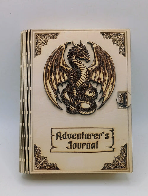 A wooden box titled 'Adventurer's Journal' featuring a carved dragon emblem on the cover